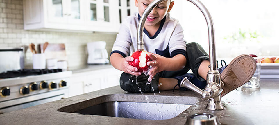 Boy washing apple in kitchen